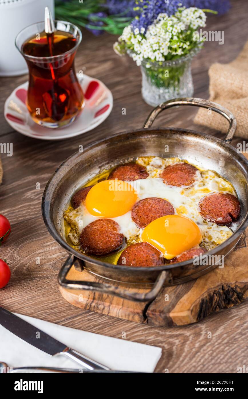 Colazione turca tradizionale - uovo fritto con salsiccia turca. Pane, pomodoro e tè Foto Stock