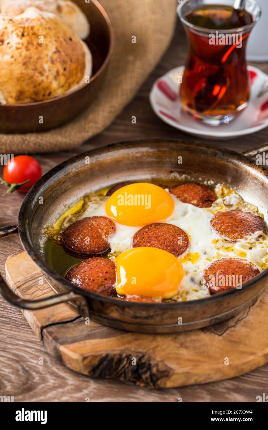 Colazione turca tradizionale - uovo fritto con salsiccia turca. Pane, pomodoro e tè Foto Stock