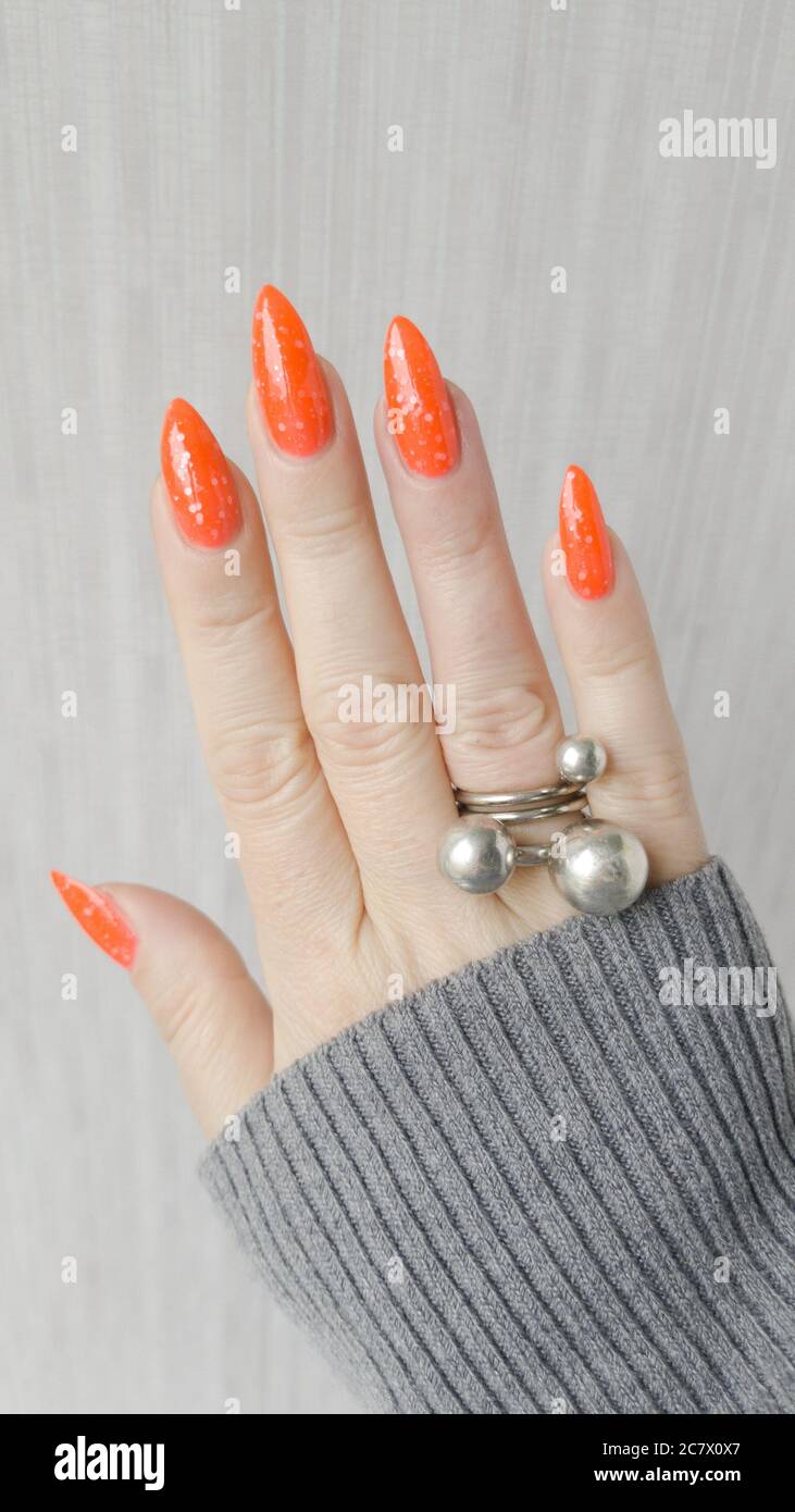La mano della donna con unghie lunghe e manicure di zenzero arancione tiene  una bottiglia di smalto per unghie Foto stock - Alamy