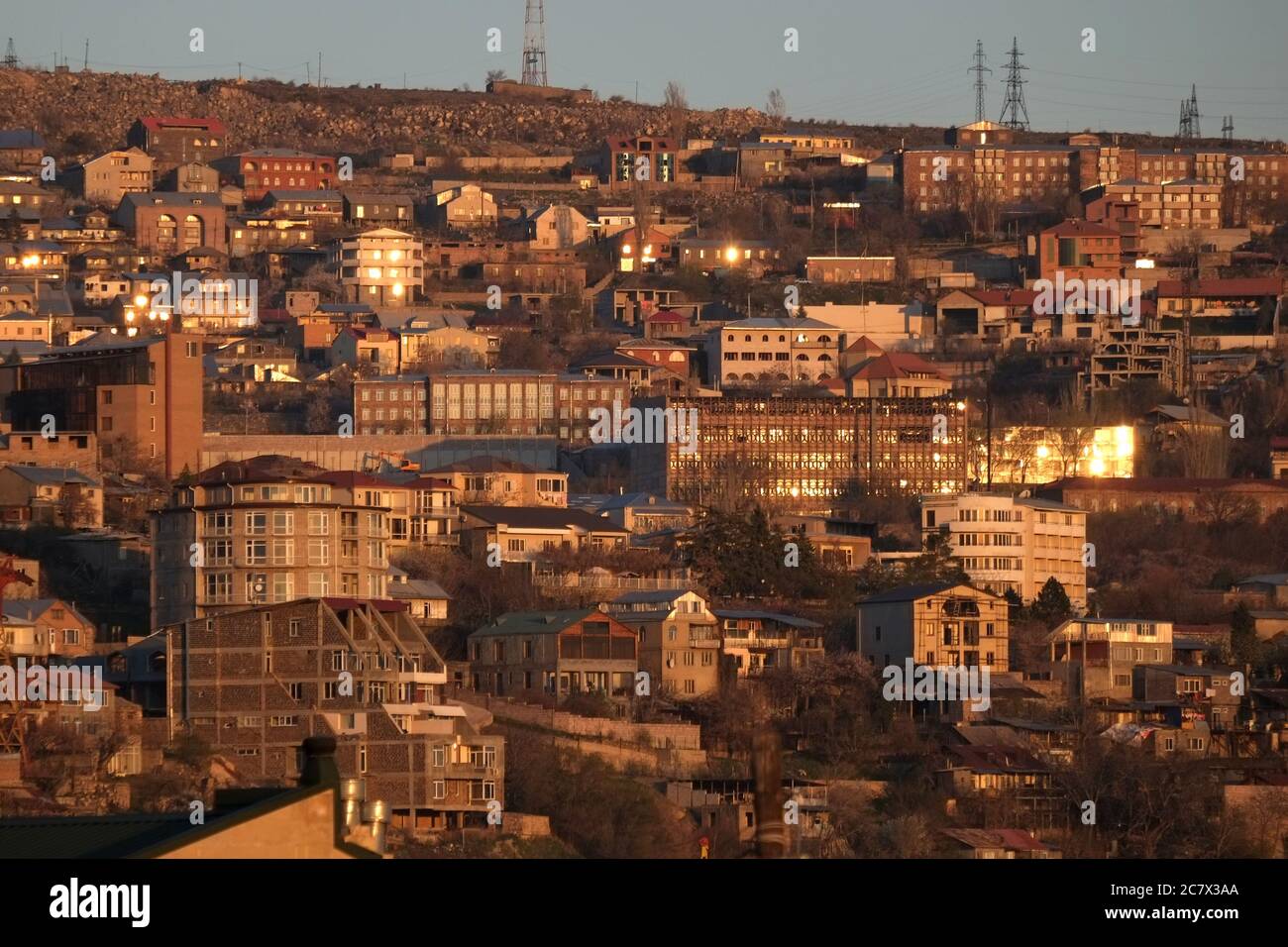 Il tramonto dorato si riflette nelle finestre degli edifici su una collina a Yerevan, Armenia Foto Stock