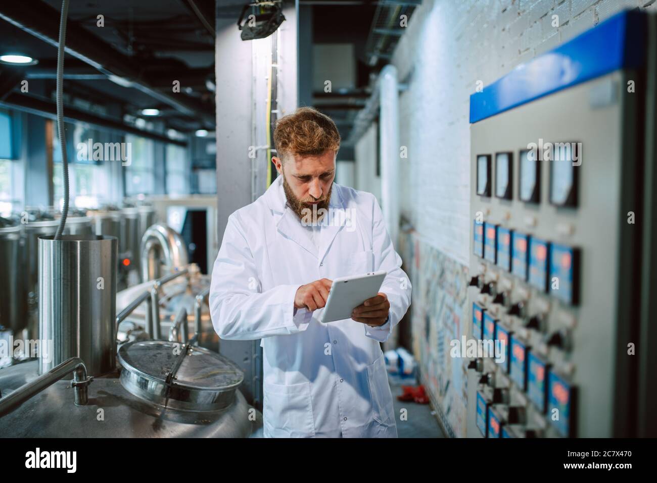 Professionista caucasico bel tecnologo in bianco uniforme standing in fabbrica farmaceutica o alimentare - produzione di controllo impianti Foto Stock