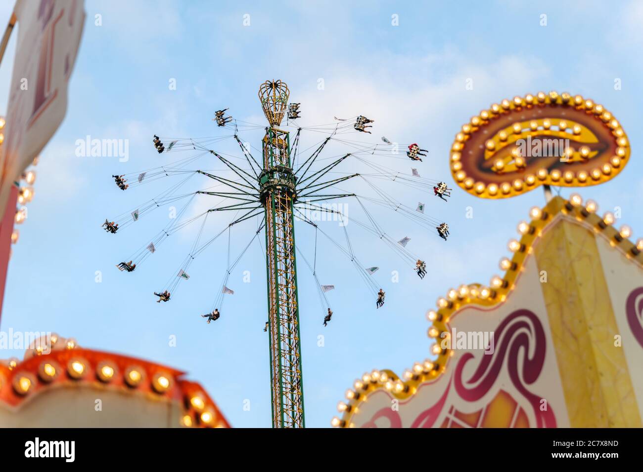 Vista ad angolo basso del giro in torre con persone emozionanti sul sedile, alzarsi, girare e cadere al Carnevale, parco divertimenti o fiera di divertimento. Foto Stock