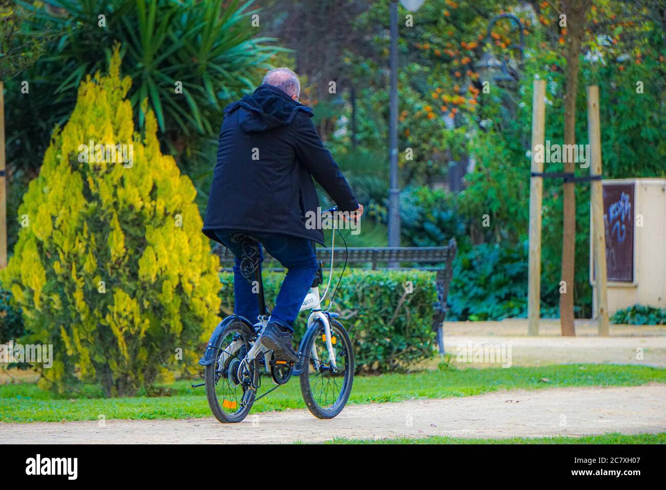 Primo piano di un maschio che cavalcano una bicicletta all'aperto circondato da alberi e cespugli Foto Stock