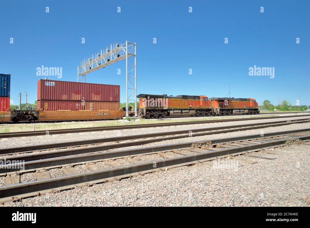 Aurora, Illinois, Stati Uniti. Due locomotive conducono un treno merci intermodale Burlington Northern Santa Fe attraverso una torre di segnale. Foto Stock