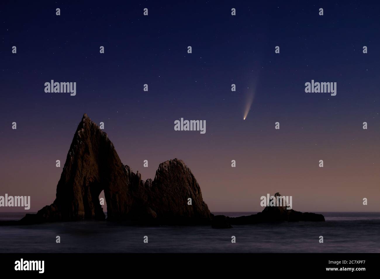 Comet Neoswise passando sopra Shark fin Rock sulla spiaggia di Martin, California del Nord, USA in una notte limpida lungo la costa Foto Stock