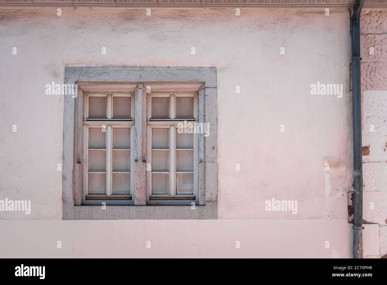 Primo piano di una finestra di legno su una vecchia pietra parete dipinta in rosa Foto Stock