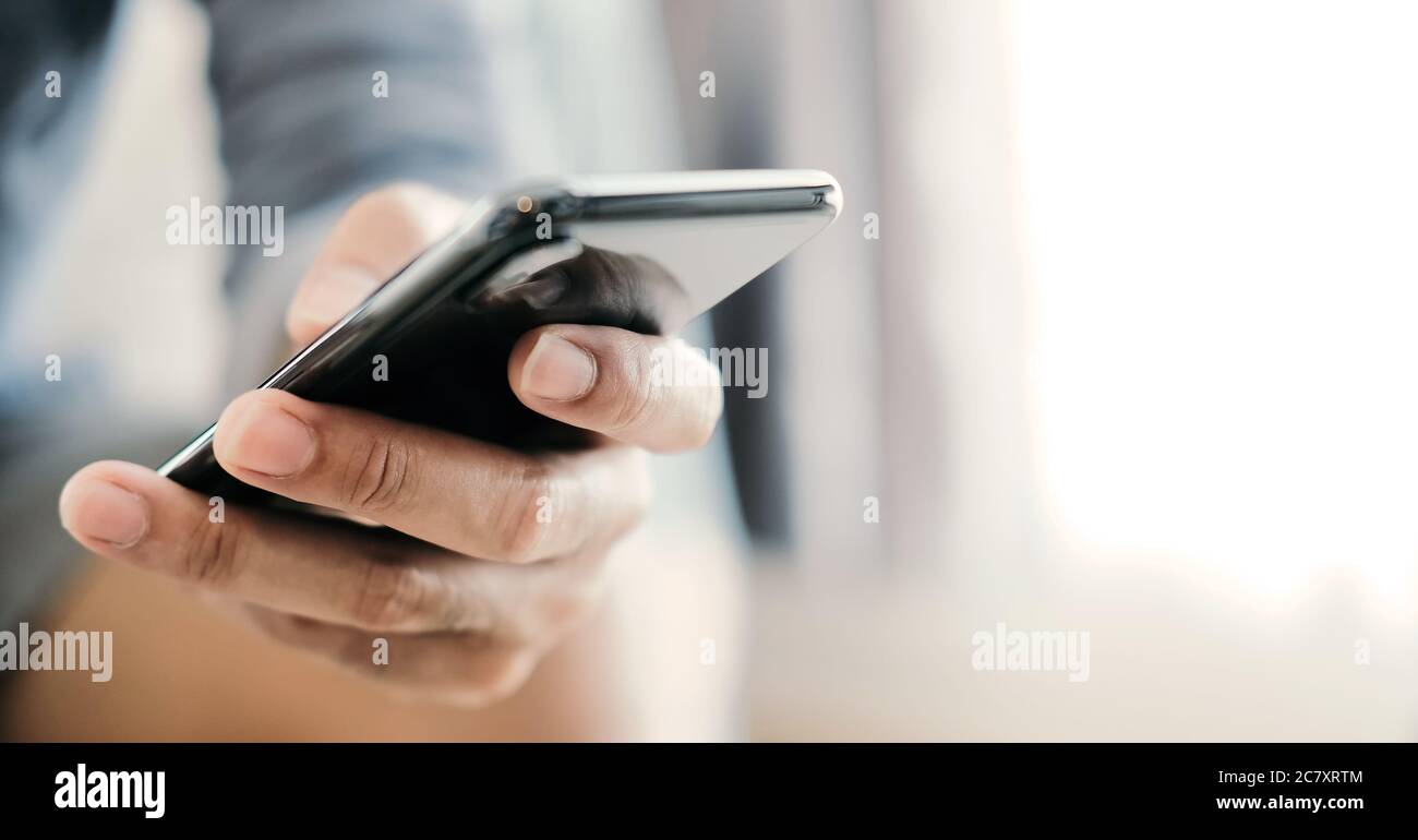 Primo piano uomo che usa lo smartphone a casa Foto Stock