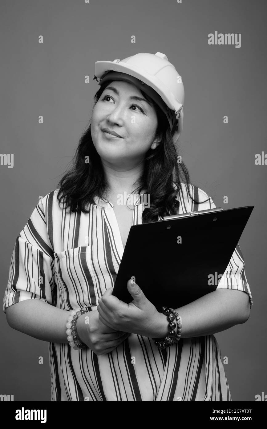 Ritratto di bella donna d'affari asiatica matura come ingegnere con appunti Foto Stock