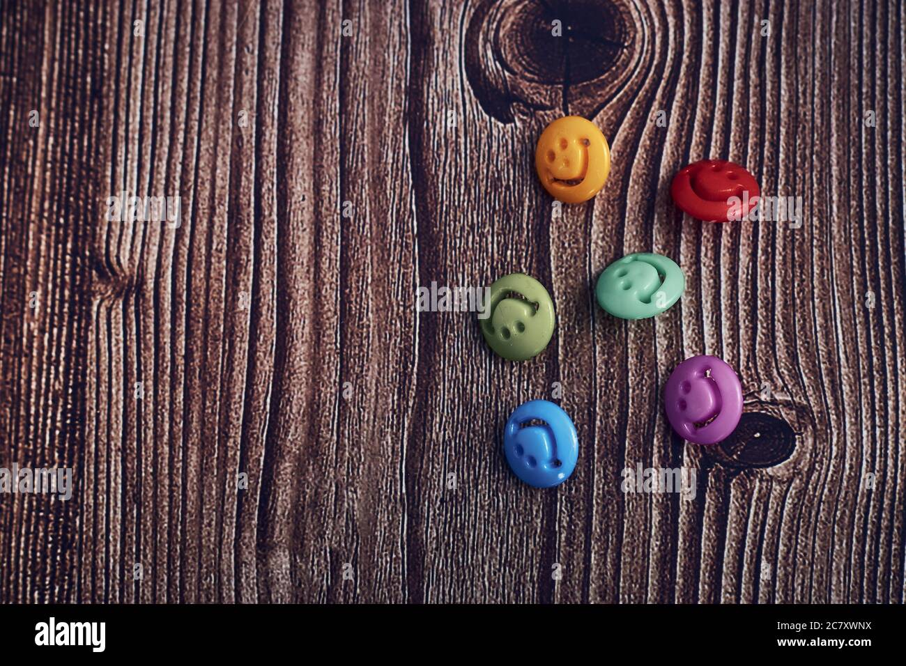 Primo piano di bottoni colorati con volti sorridenti su uno tavolo