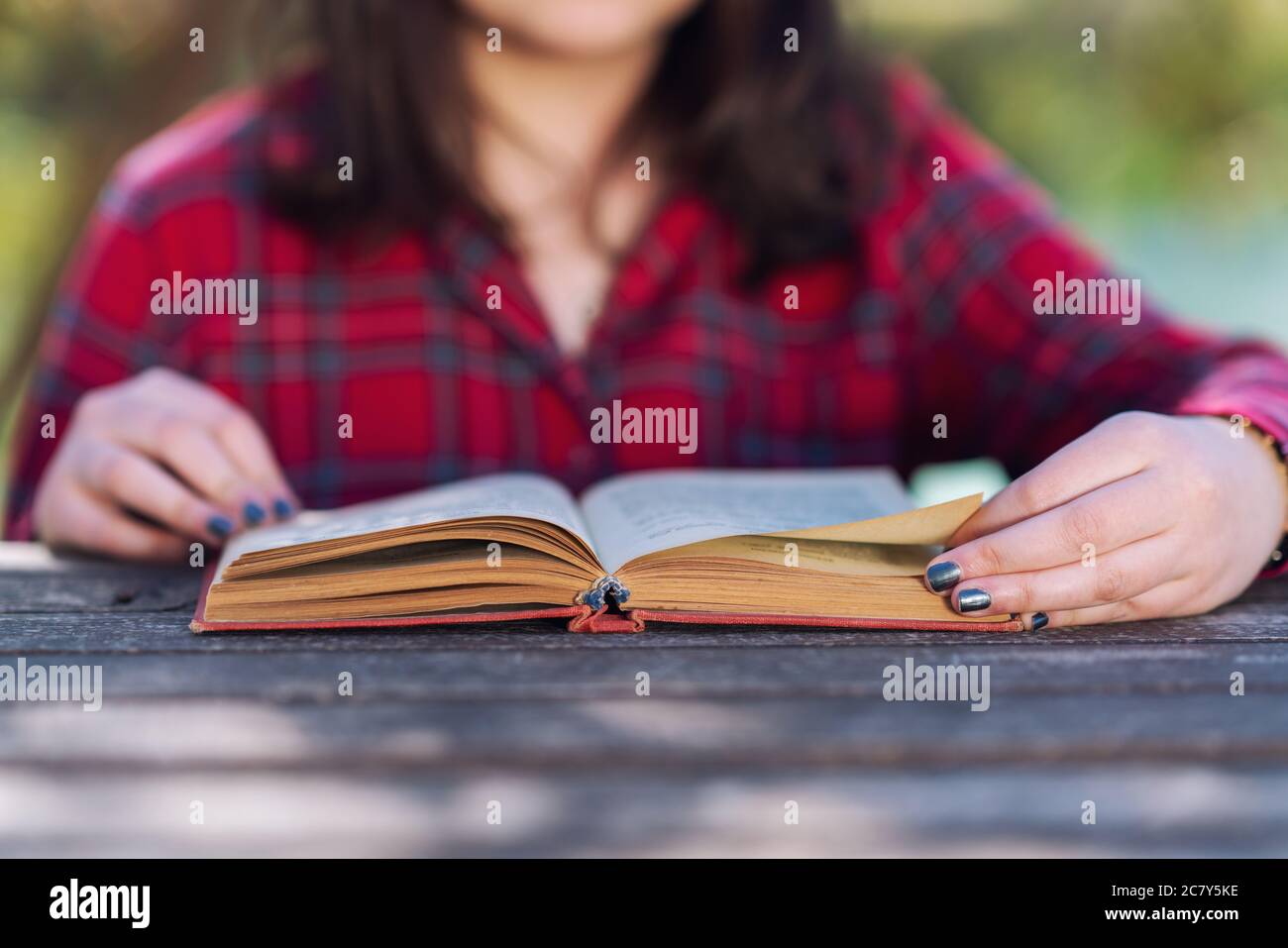 Primo piano di una ragazza seduta e leggendo un libro o studiando con i libri in un parco. Foto di alta qualità Foto Stock