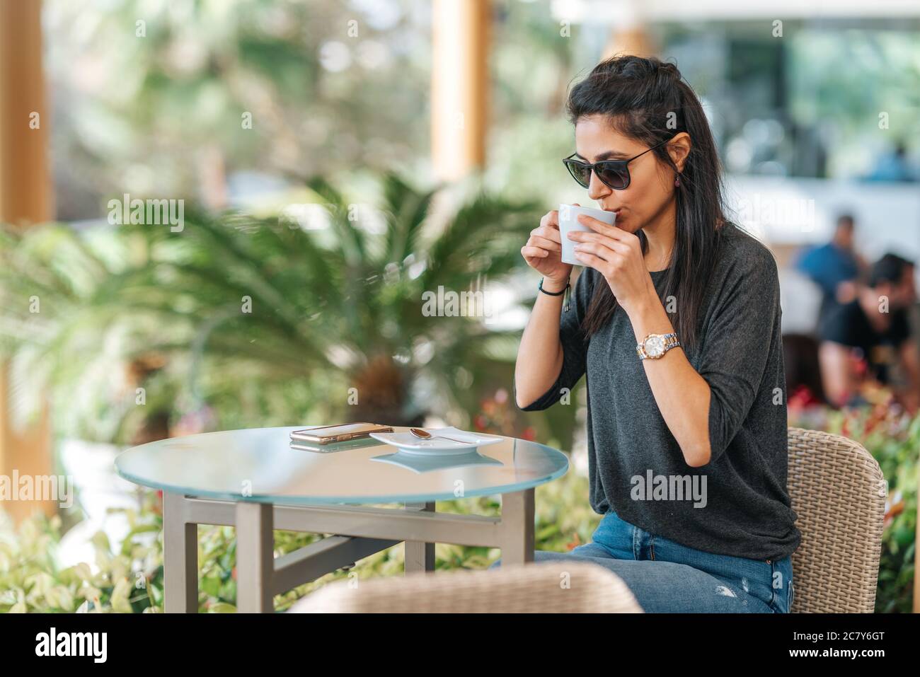 La giovane donna è seduta e beve una tazza di bevanda calda in un caffè elegante. . Foto di alta qualità Foto Stock