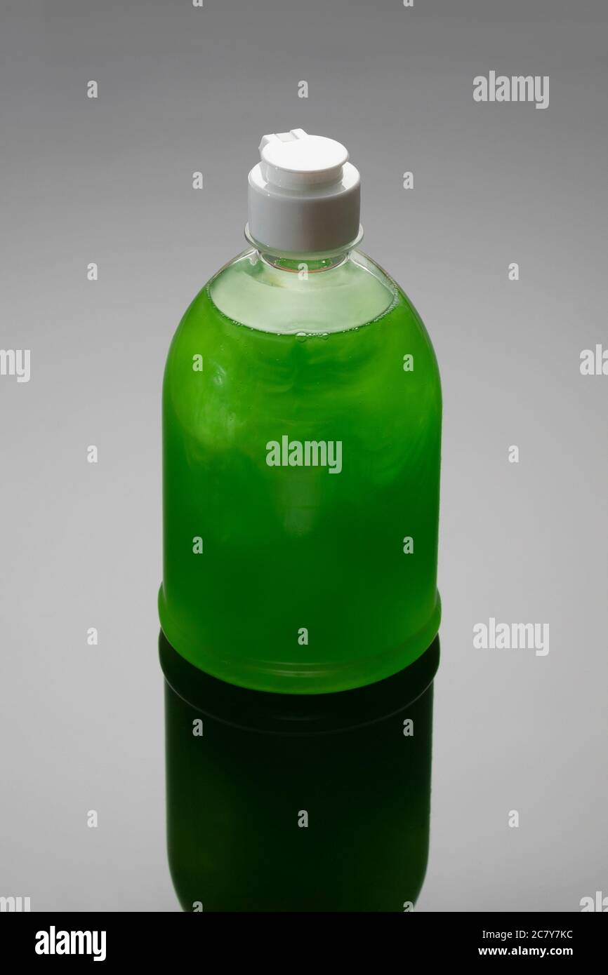 Flacone di sapone su sfondo grigio con ombra. Liquido per lavastoviglie di colore verde. Foto Stock