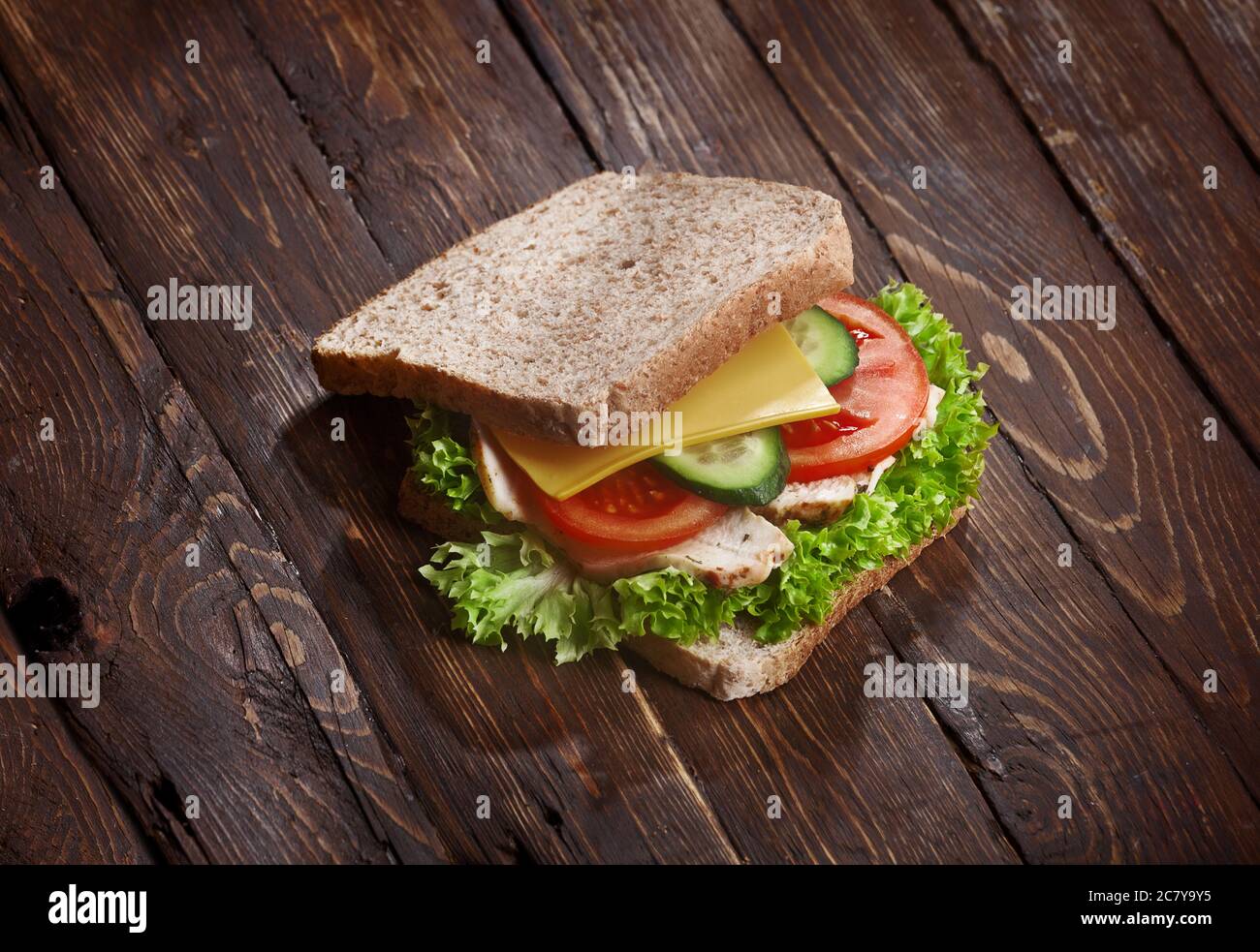 tacchino sandwich primo piano con pomodori freschi, foglie di insalata di lattuga, cetriolo e formaggio, su sfondo rustico di legno, nessuno Foto Stock