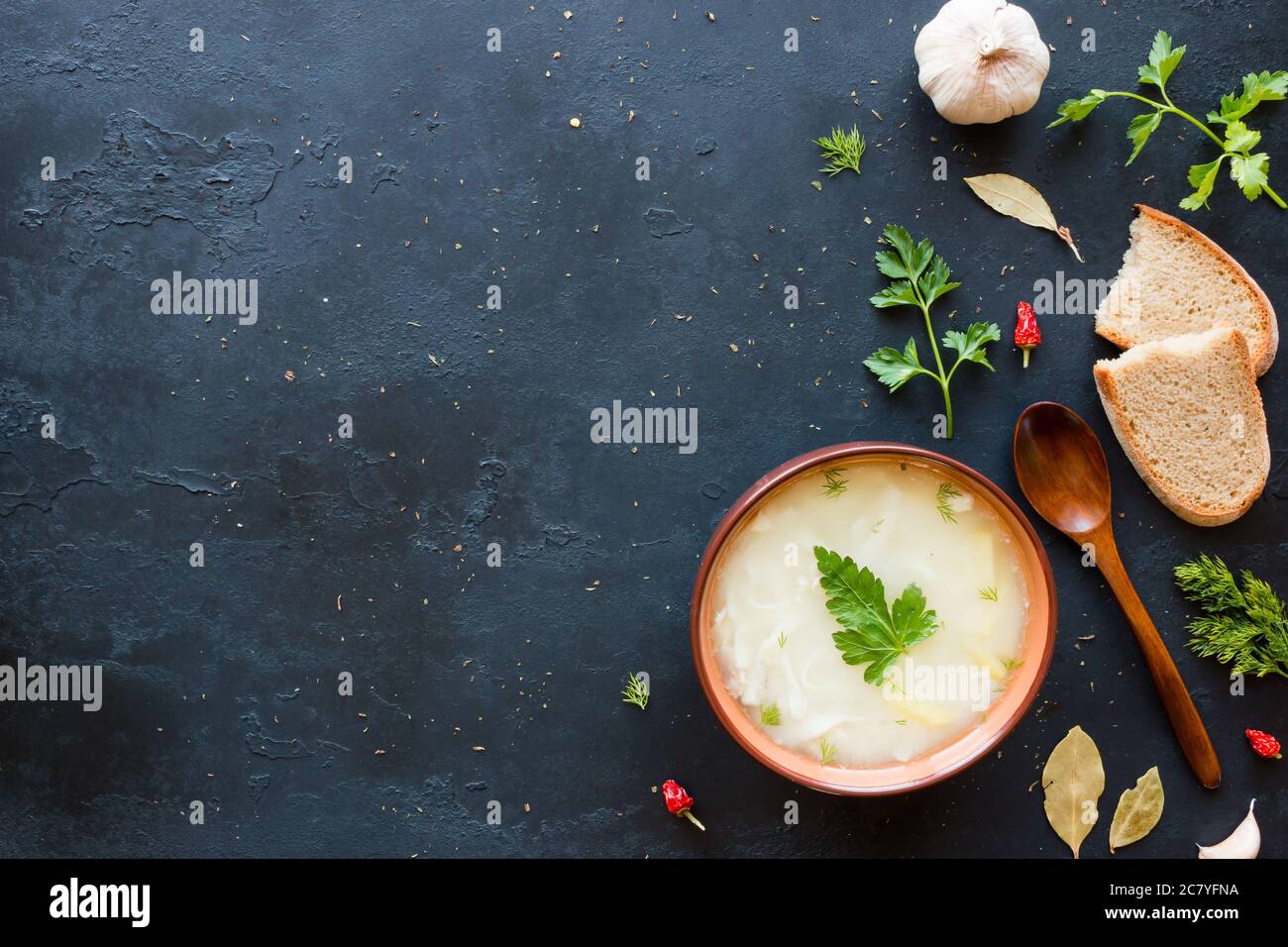 Zuppa di pollo con tagliatelle, prezzemolo, aneto, spezie e pane su sfondo nero con spazio per il testo Foto Stock
