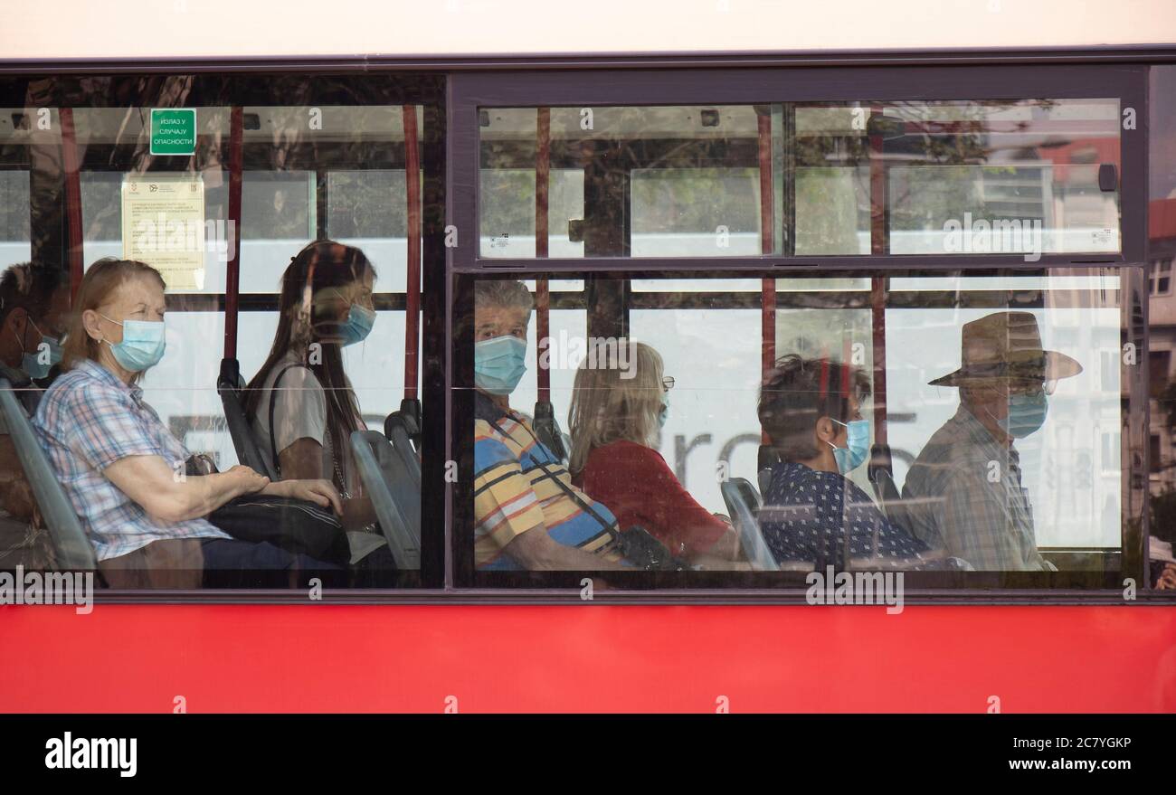 Belgrado, Serbia - 16 luglio 2020: Persone che indossano maschere chirurgiche mentre si siedono e si cavalcano in una finestra di un autobus in movimento, dall'esterno Foto Stock