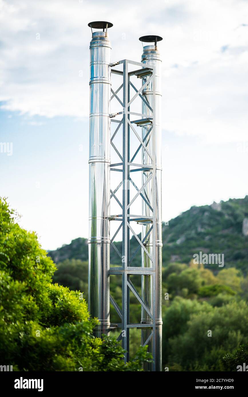 Tubi galvanizzati di piccola centrale elettrica moderna su sfondo cielo. Torre in acciaio con due tubi in acciaio collegati con barre diagonali. Foto Stock