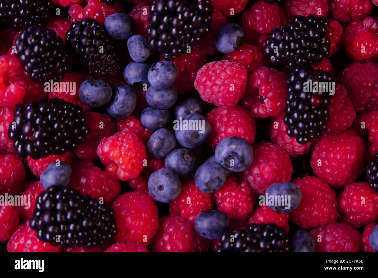 Composizione di bacche fresche. Lamponi, more e mirtilli su sfondo nero. Gustosa frutta organica ricoperta di rugiada. Foto Stock