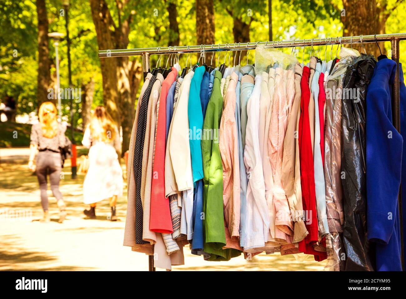 Eleganti abiti vintage colorati in vendita al mercato di strada in Francia  in sole primavera giorno. Silhouette di due giovani donne sfocate che  camminano sullo sfondo Foto stock - Alamy
