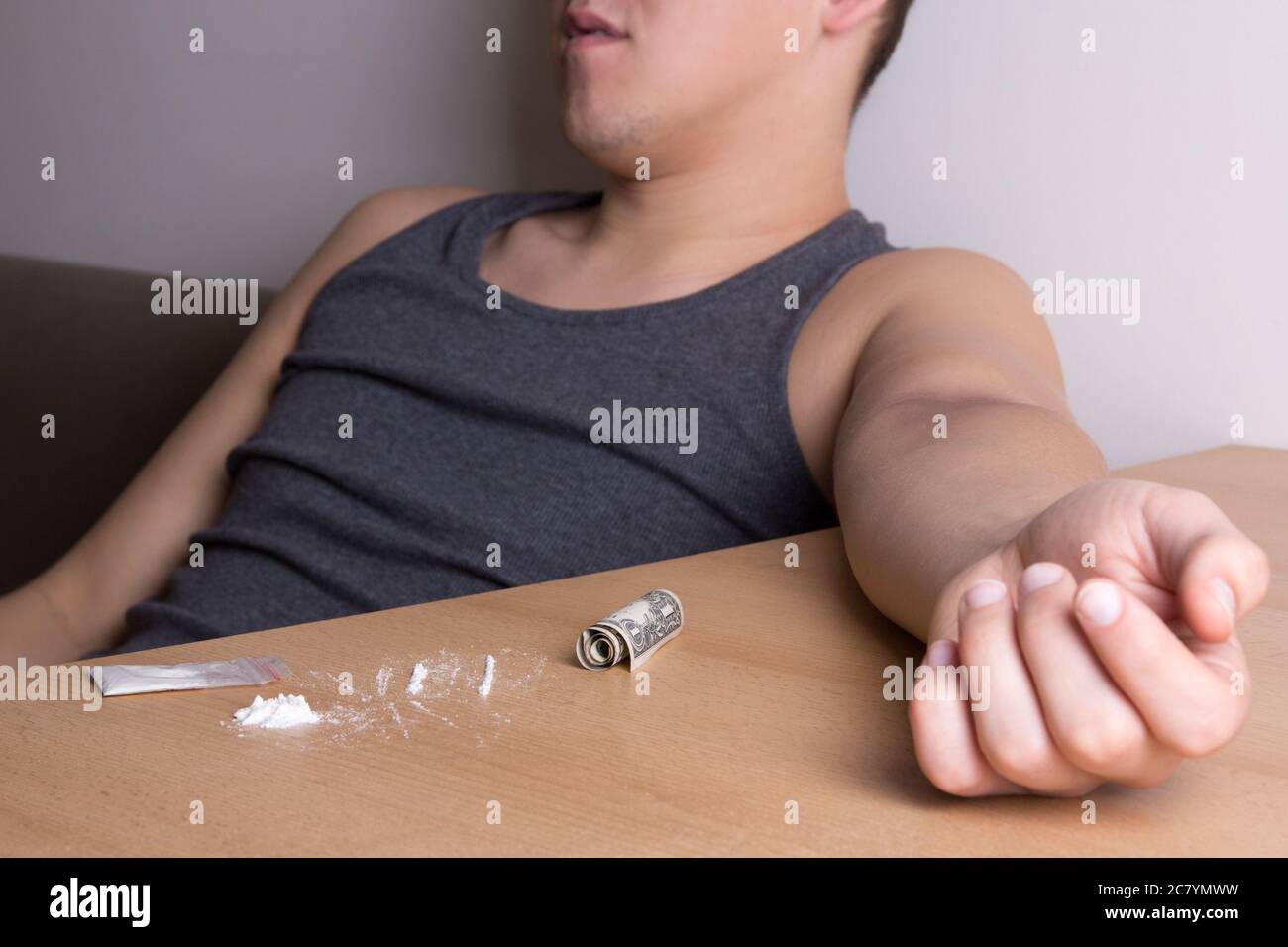 giovane addicted uomo con polvere di cocaina e dollaro sul tavolo Foto Stock