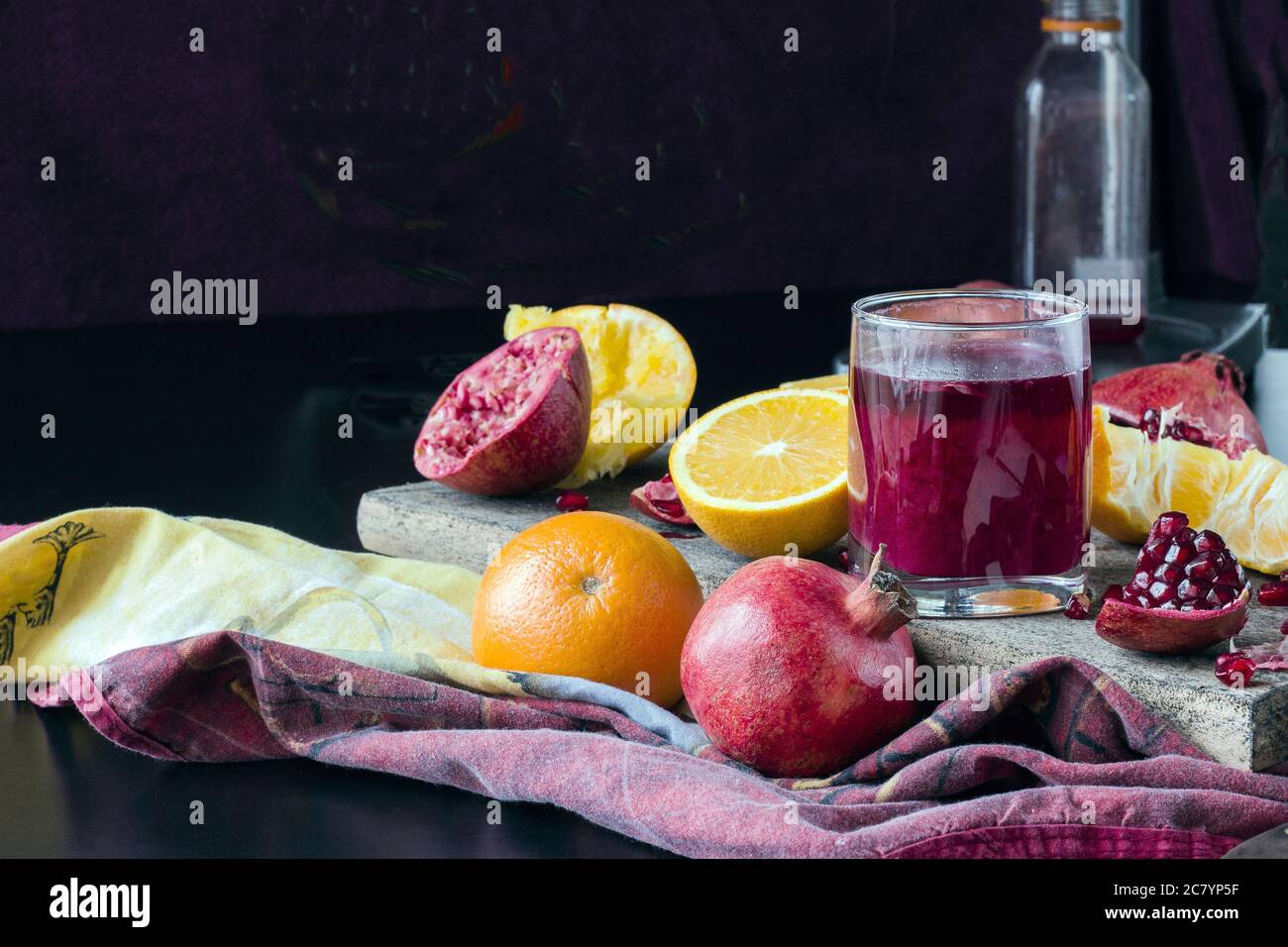 bicchiere di succo di melograno appena spremuto, frutta fresca tagliata a pezzi, il processo di spremitura del succo Foto Stock