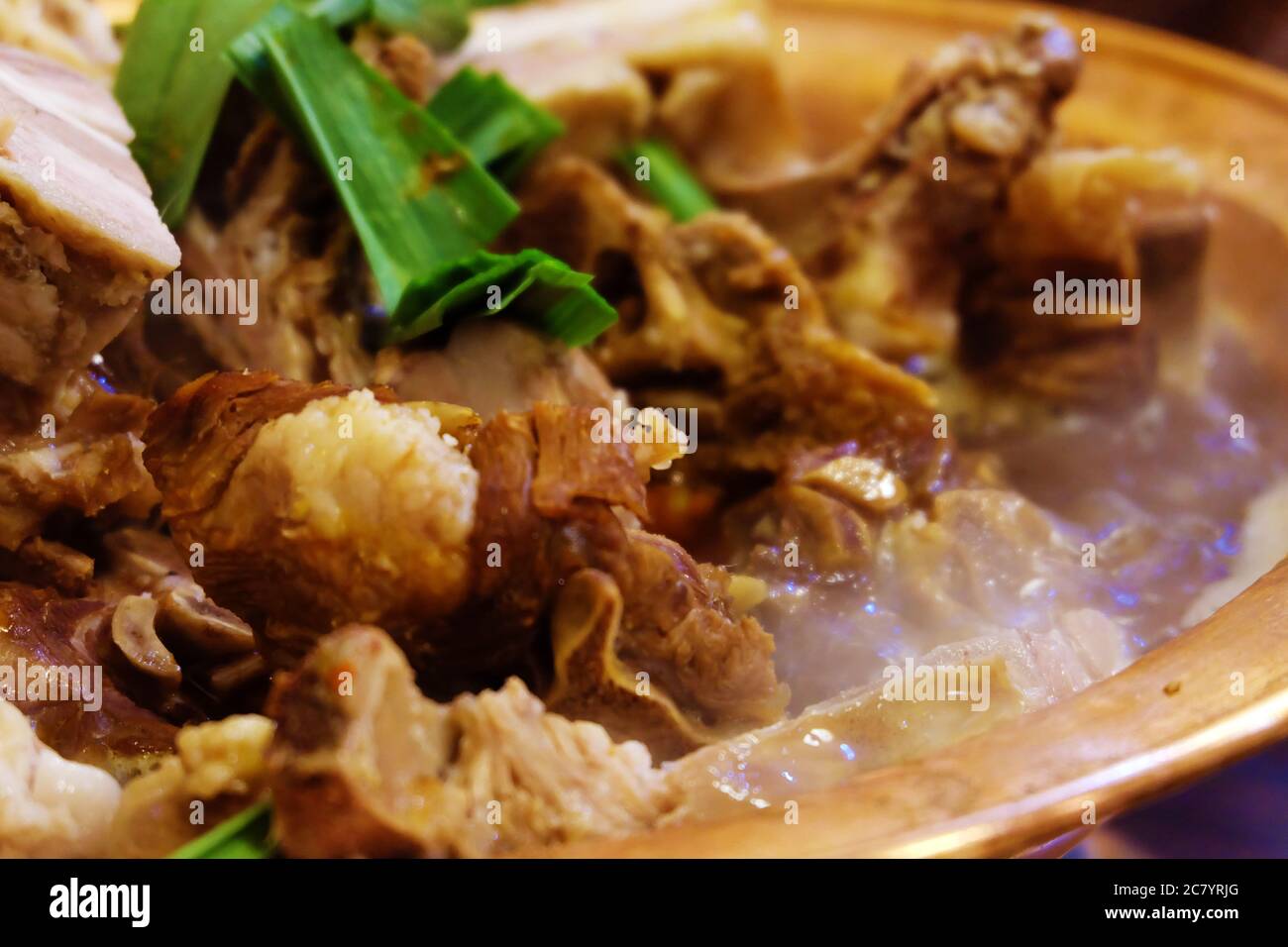 Primo piano su delizioso piatto cinese caldo. Grandi pezzi di carne e cipolla verde. Acqua bollente per zuppa. Sfondo sfocato Foto Stock