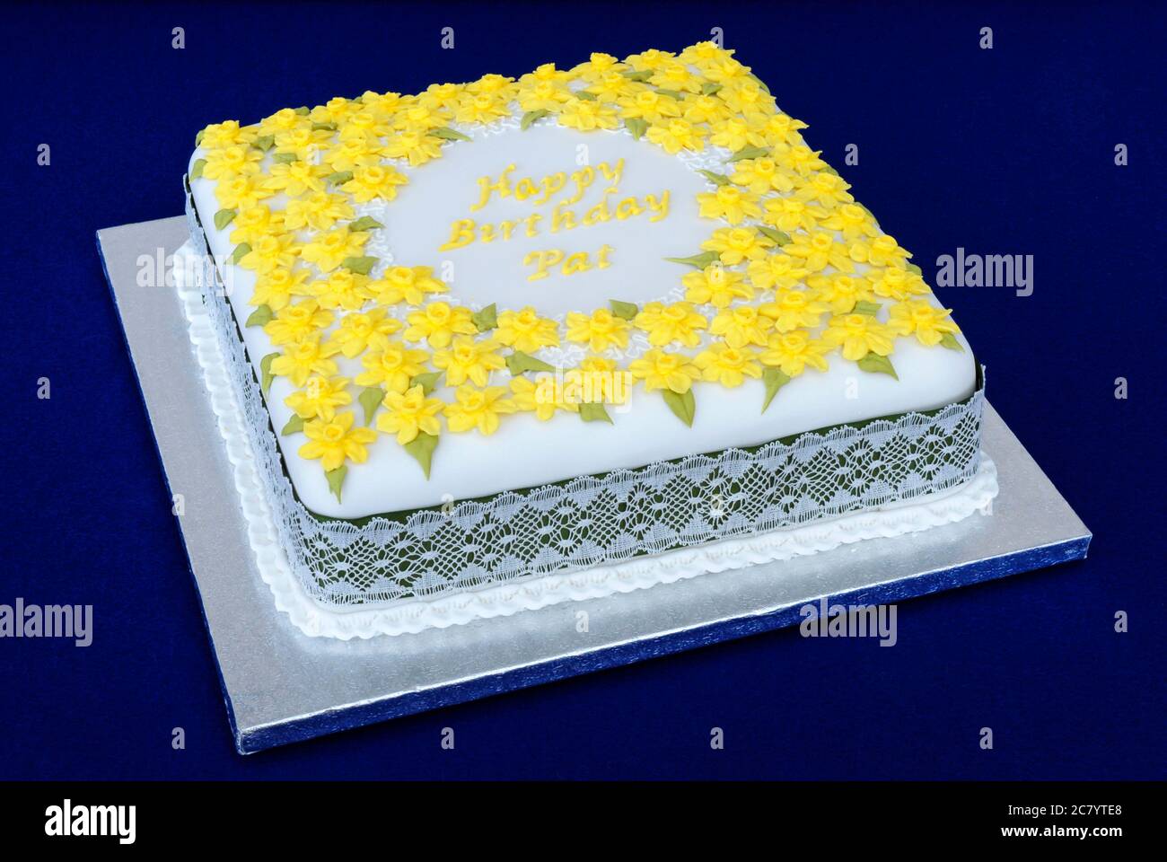 Torta di compleanno con zucchero quadrato, decorata con molti fiori gialli e il saluto 'buon compleanno'. Foto Stock