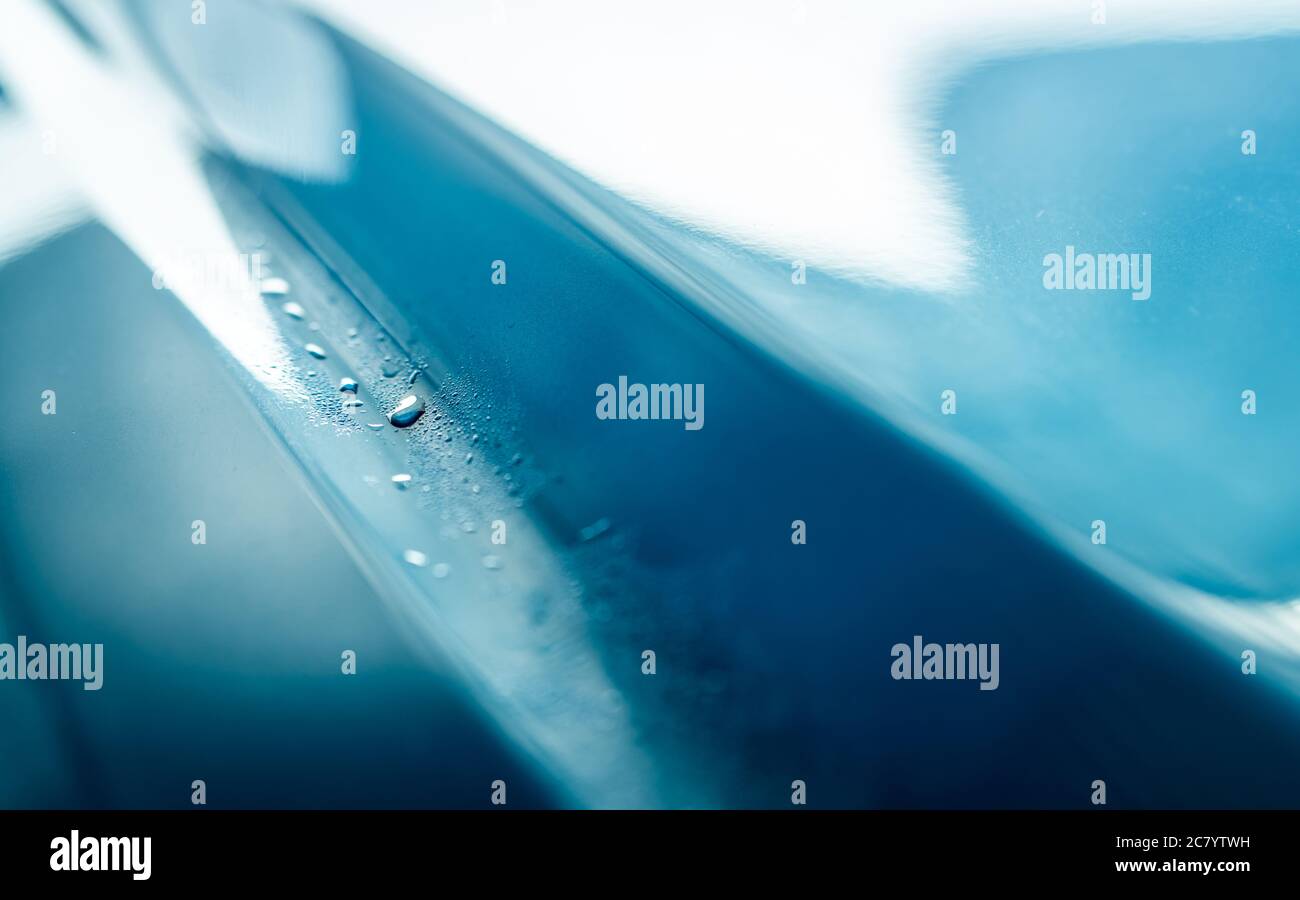 Closeup lucido blu auto texture con gocce d'acqua. L'auto blu si sta lavando con acqua. Attività di cura automatica. Auto con gocce d'acqua dopo la pulizia con alto Foto Stock