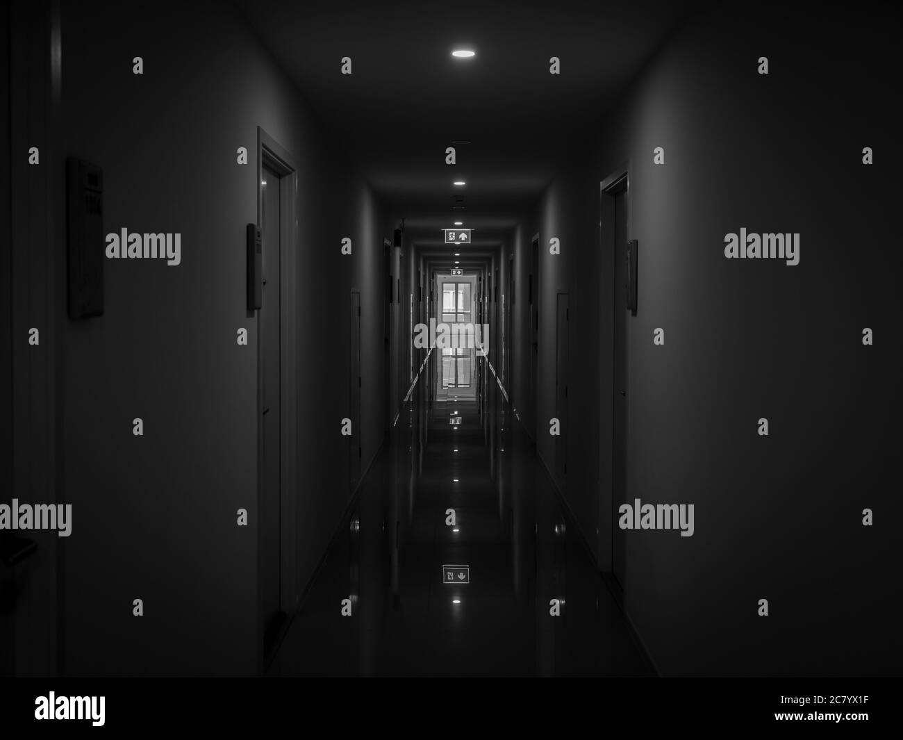 Misterioso corridoio scuro nell'edificio. Camera porta prospettiva in un edificio solitario tranquillo con luce di uscita fuoco sul soffitto in stile bianco e nero. ho Foto Stock