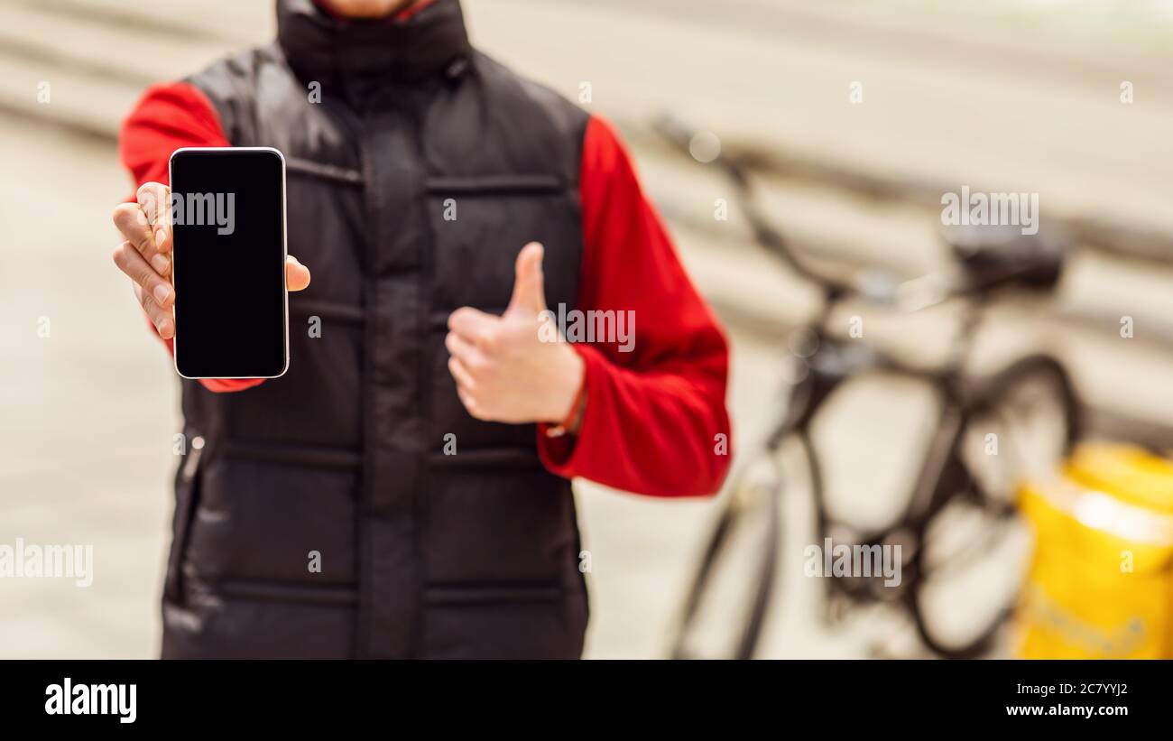 Corriere che mostra schermo del telefono che consegna il cibo sulla bicicletta all'aperto, tagliato Foto Stock