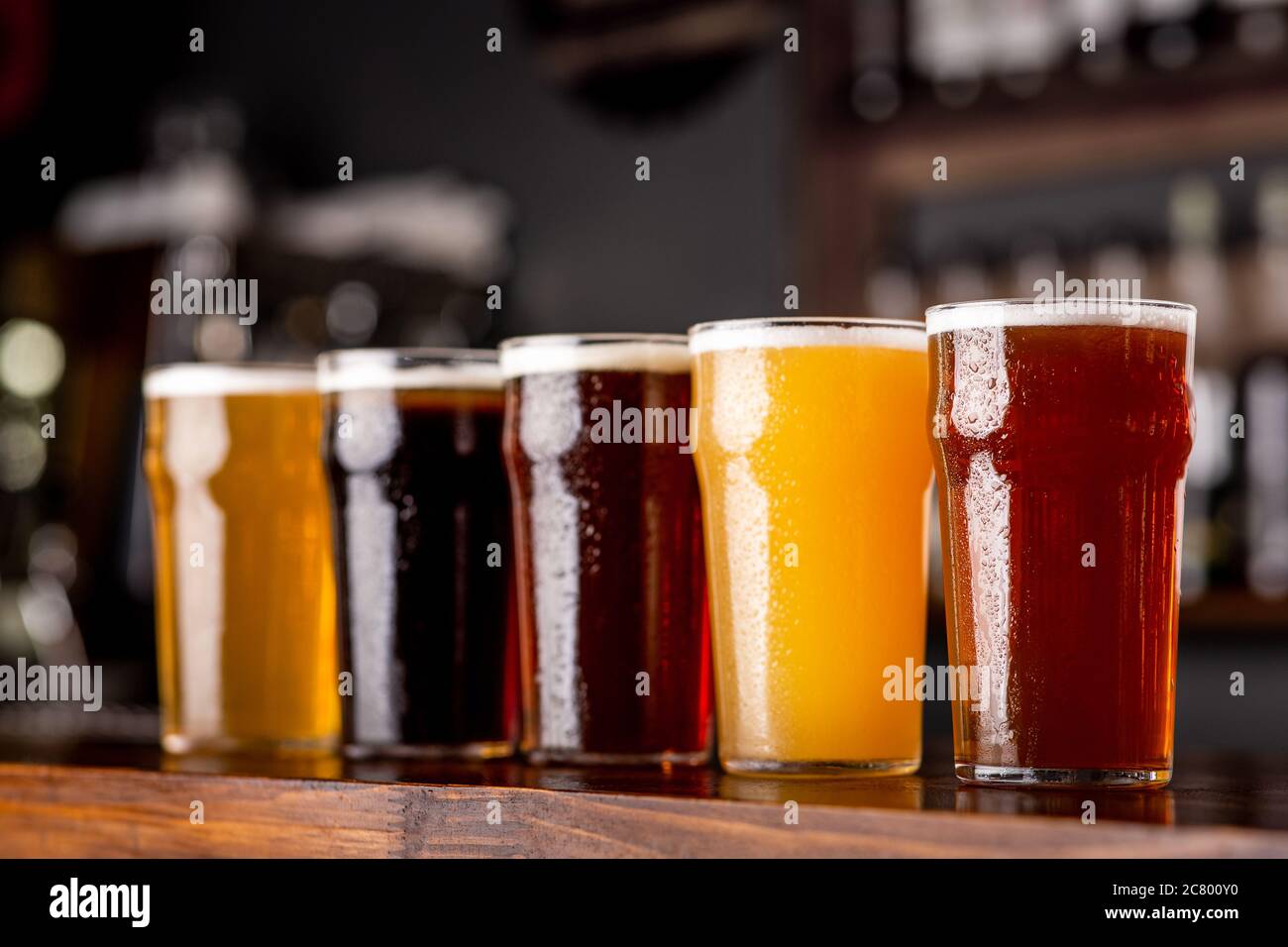 Birra artigianale e industria. Birra chiara, chiara e scura, non filtrata in bicchieri su bancone di legno Foto Stock