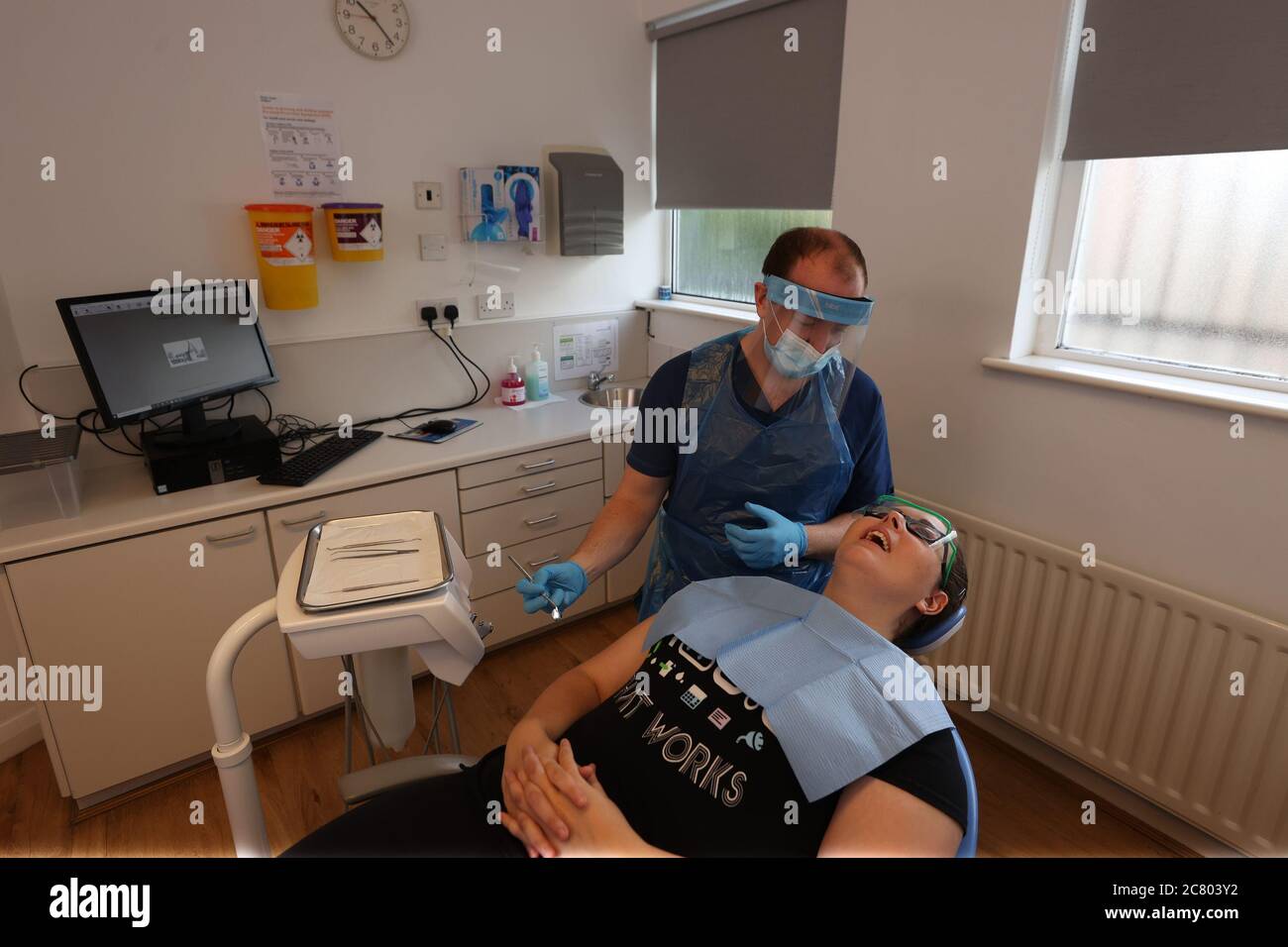 Il dentista Dr Allan Clarke con il dentista Dr Danielle Magee indossando PPE per mostrare nuove procedure di divaricamento sociale in una pratica a Belfast. Foto Stock