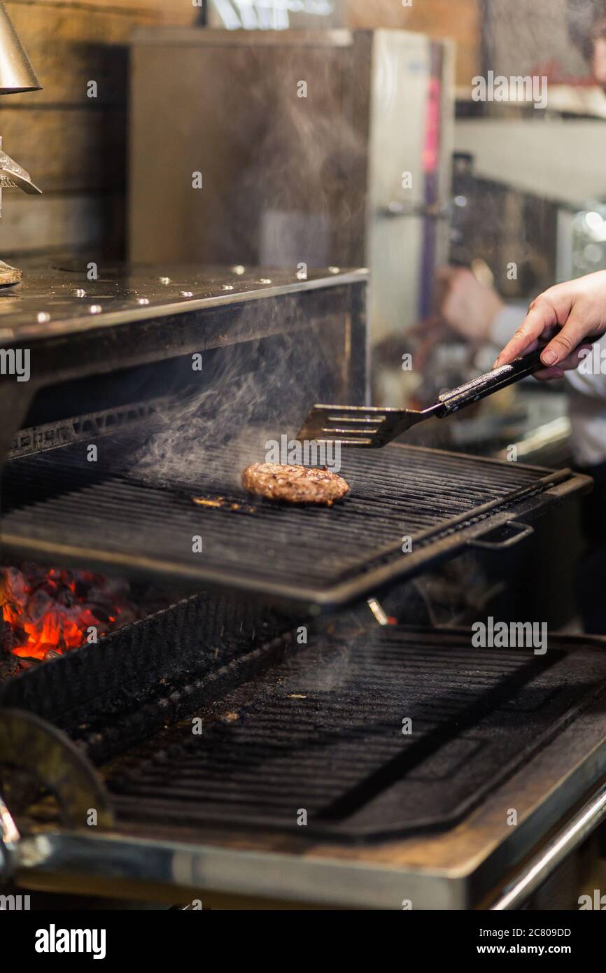 Uomo che grigliano carne su griglia barbecue. Grigliate alla perfezione Foto Stock