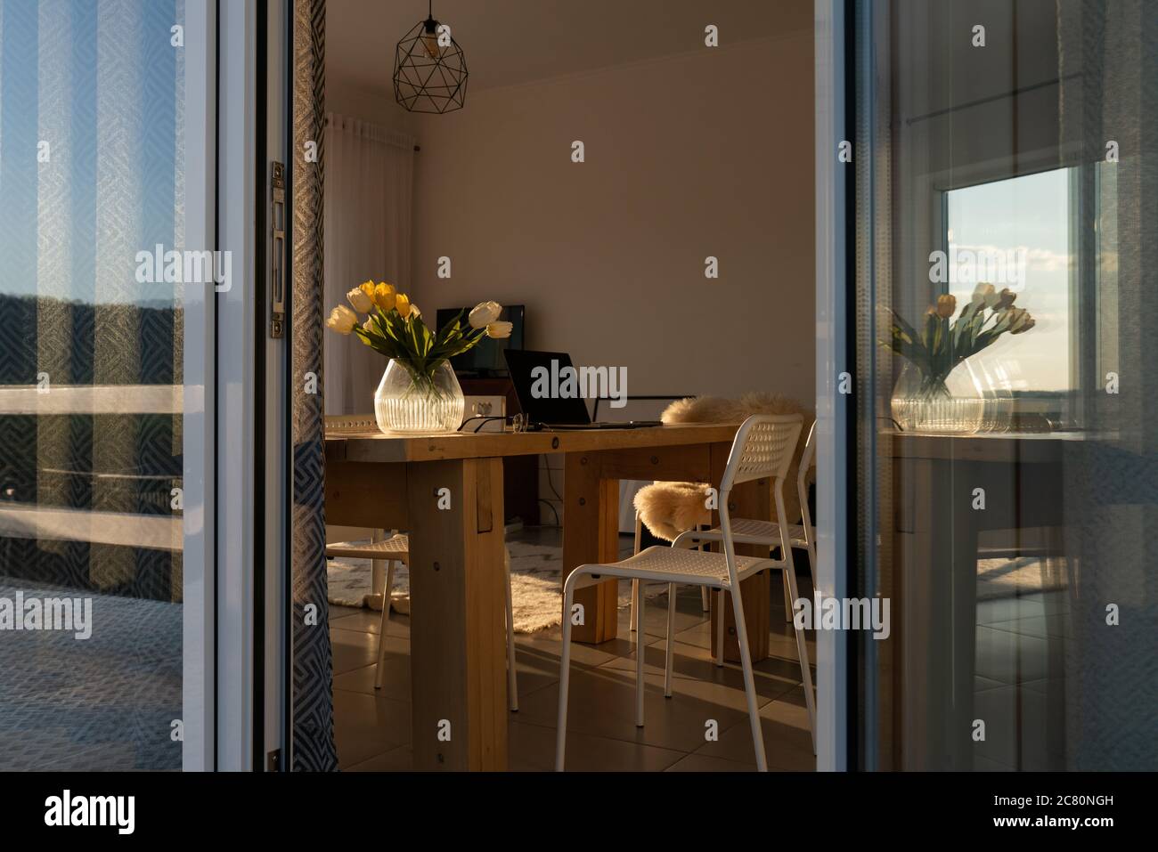 Design moderno. Interno di sala da pranzo luminosa decorata con fiori. Computer portatile su un tavolo Foto Stock