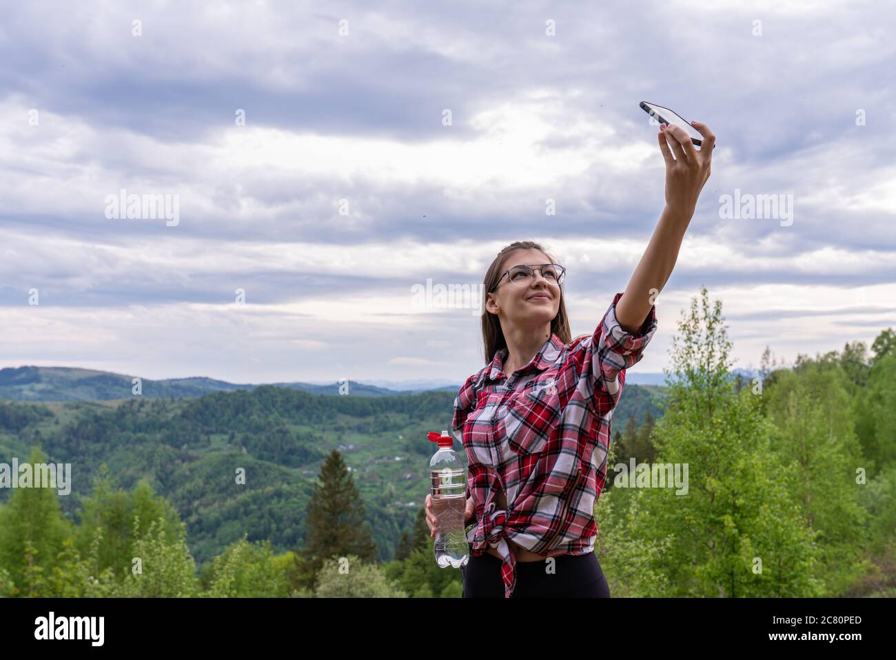Bella giovane turista femminile fa selfie in montagna. Donna viaggiatore che prende selfie in montagna, viaggio stile di vita avventura concetto attivo vacanze Foto Stock
