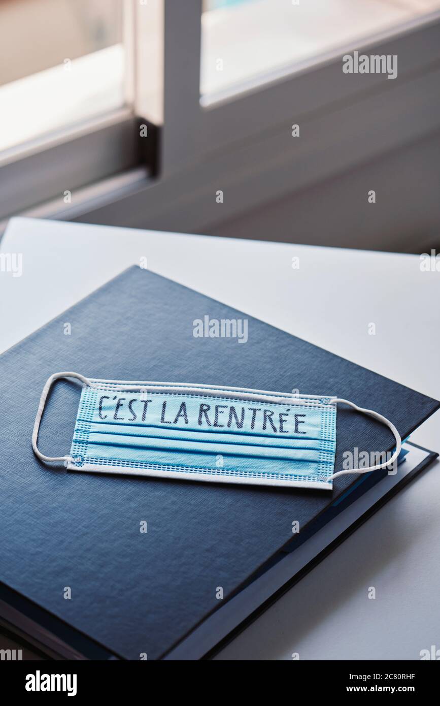primo piano di un legante e di una maschera chirurgica blu con il testo di ritorno a scuola scritto in francese, che raffigura la necessità di prevenire l'infezione a scuola in Foto Stock