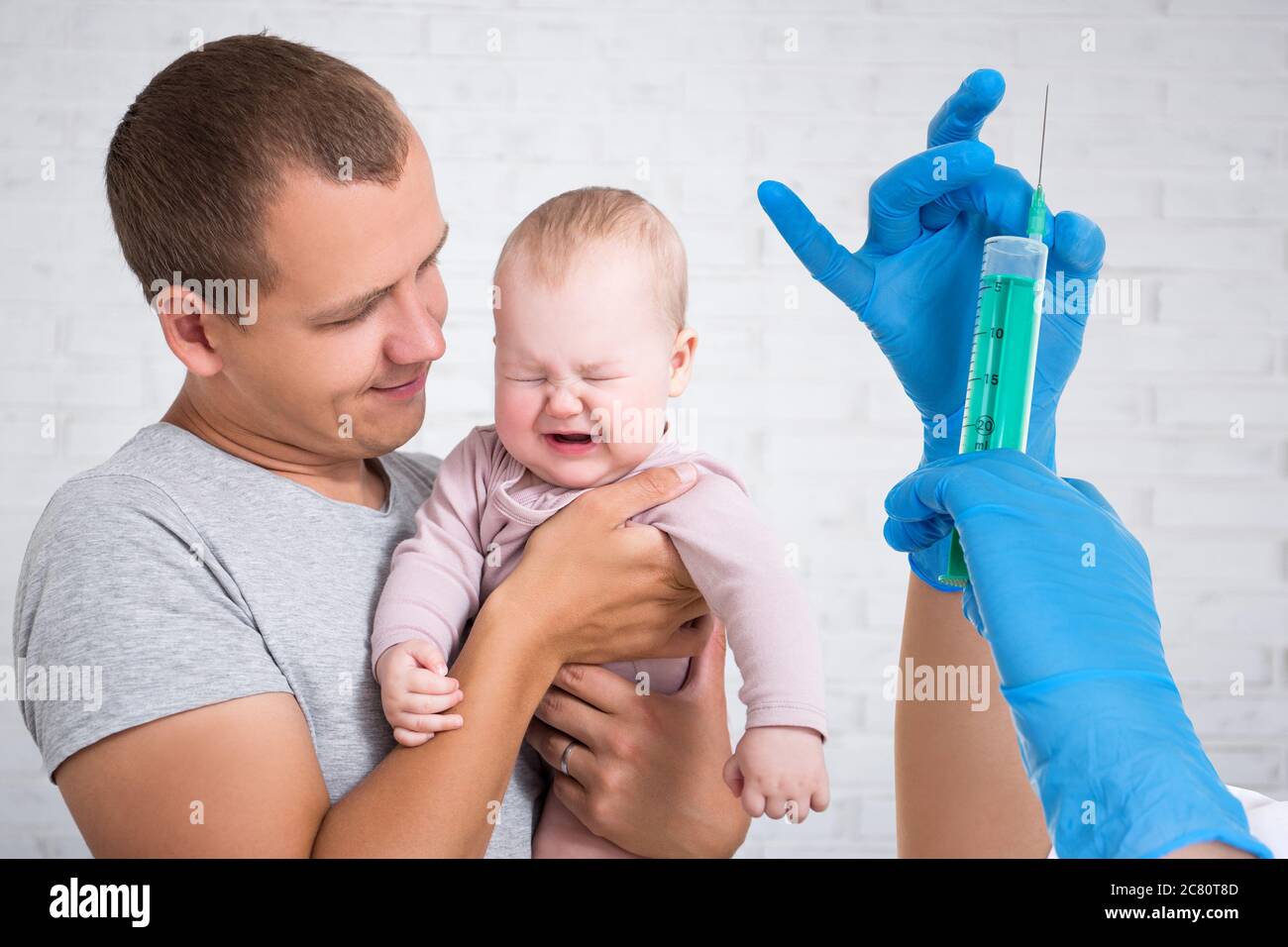 concetto di assistenza sanitaria e vaccinazione - giovane padre che tiene piangendo la bambina e le mani del medico con siringa Foto Stock