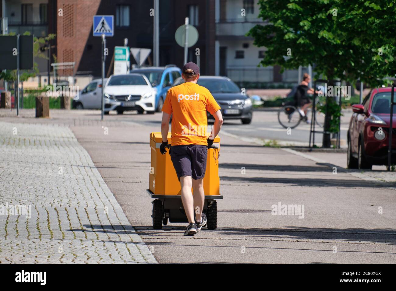 Il postino finlandese cammina per la strada con il tram. Foto Stock