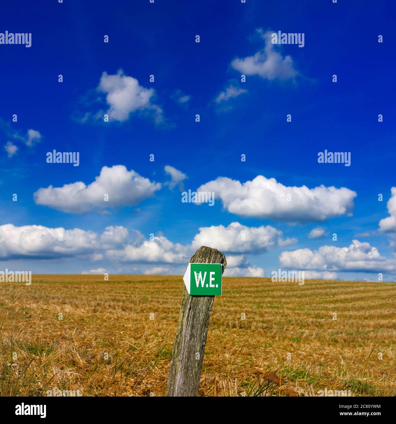 Cartello indicante la direzione in un vasto paesaggio rurale sotto un cielo azzurro pieno di nuvole, Auvergne, Francia Foto Stock