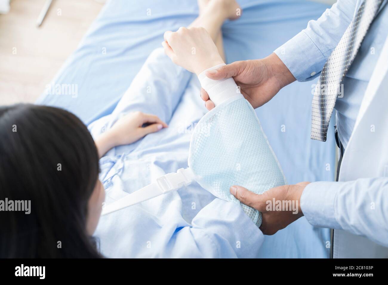 Sorridente medico che esamina il braccio di una paziente femminile mentre si siede nella sala esame medico presso la clinica. Foto Stock