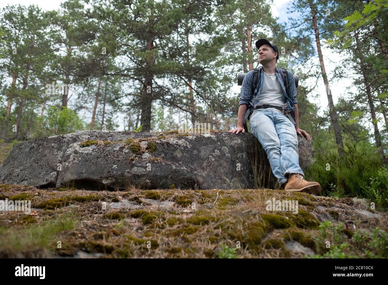 Giovane uomo caucasico trekking in foresta avendo un riposo Foto Stock
