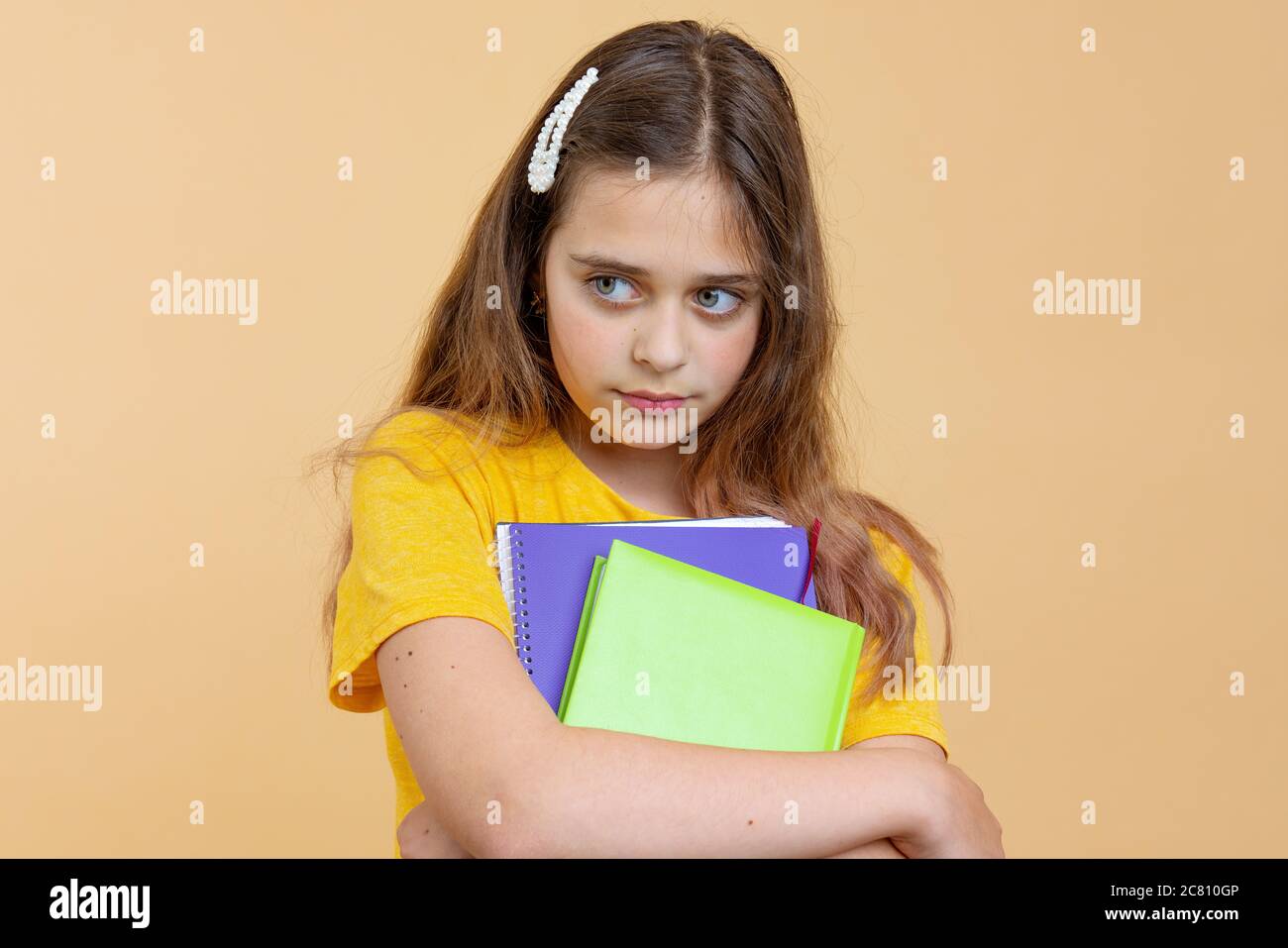 Infelice europeo americano ragazza studente teen in abiti casual tenere libri isolati sulla parete arancione sfondo studio ritratto. Istruzione nella scuola superiore Foto Stock