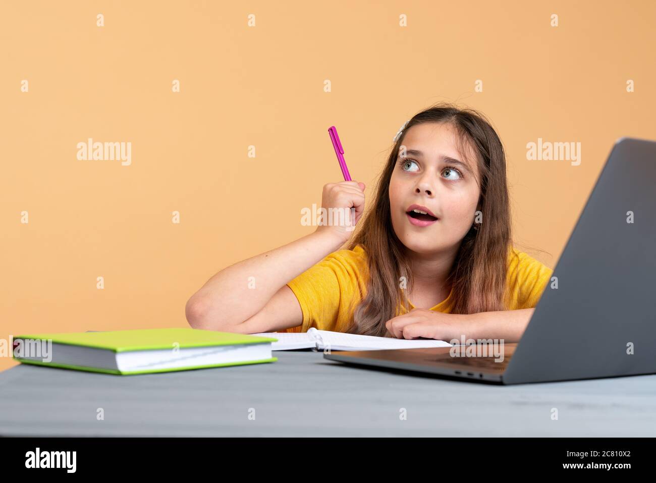 Bruna ragazza adolescente con penna in mano avendo classe scolastica online a casa Foto Stock
