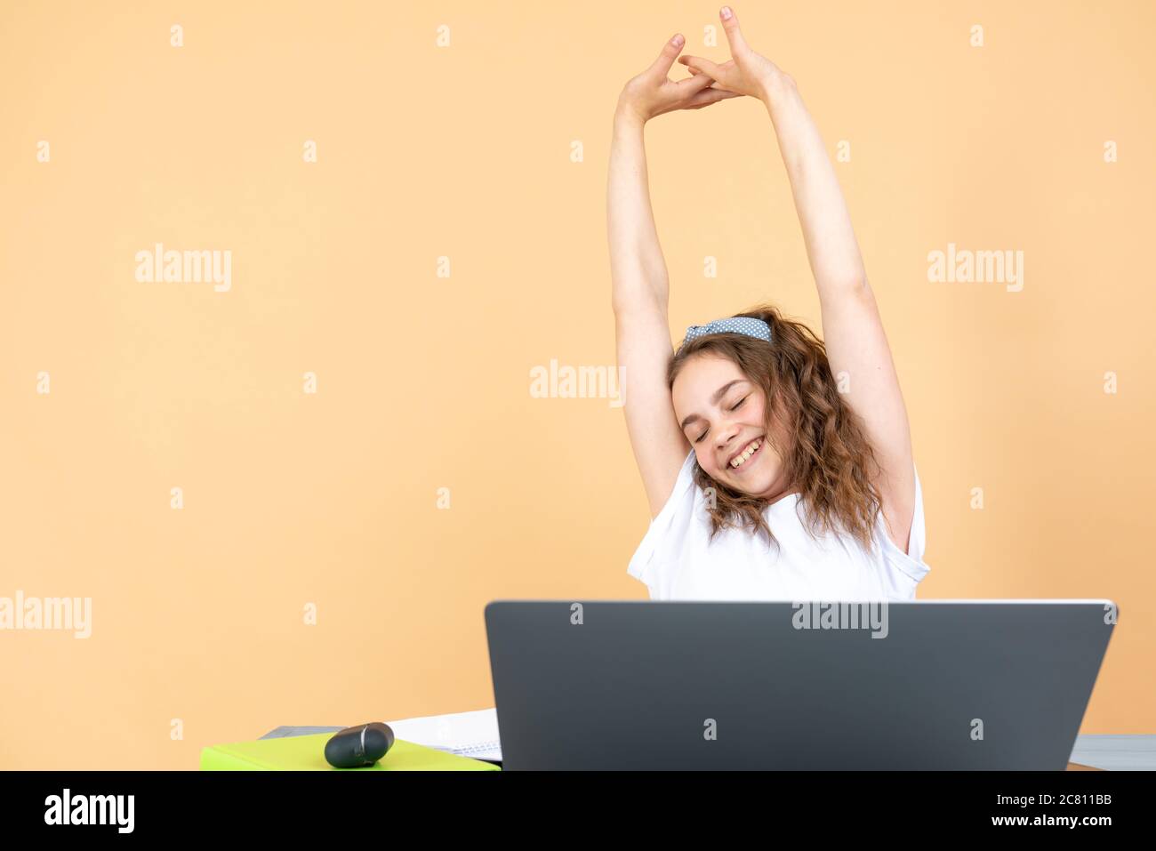 Felice studente riuscito di ragazza teen ha finito di studiare, sorridente ragazza alzando le mani soddisfatto con la soluzione che riceve buone notizie in e-mail, stretching prendendo Foto Stock