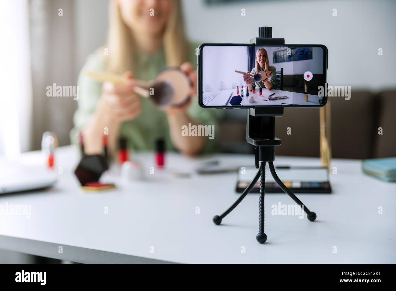 video tutorial di registrazione di makeup blogger influencer con telefono per i social media a casa Foto Stock