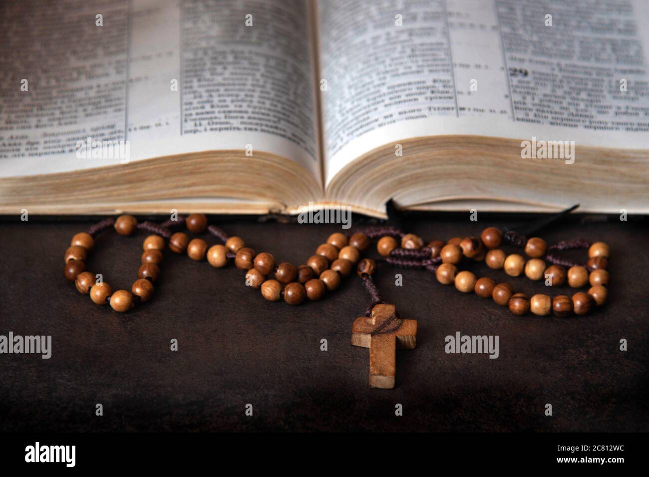 Rosario di legno e Bibbia aperta sullo sfondo. Foto Stock