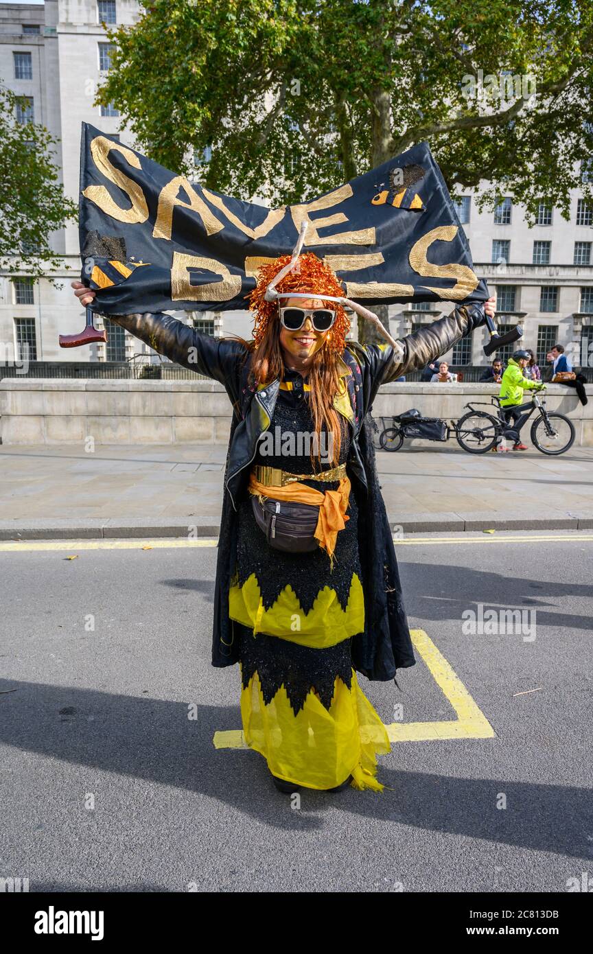 LONDRA - 18 OTTOBRE 2019: Scatto verticale a lunghezza intera del protestore della ribellione di estinzione che tiene un banner di Save Bees ad una protesta di ribellione di estinzione M. Foto Stock