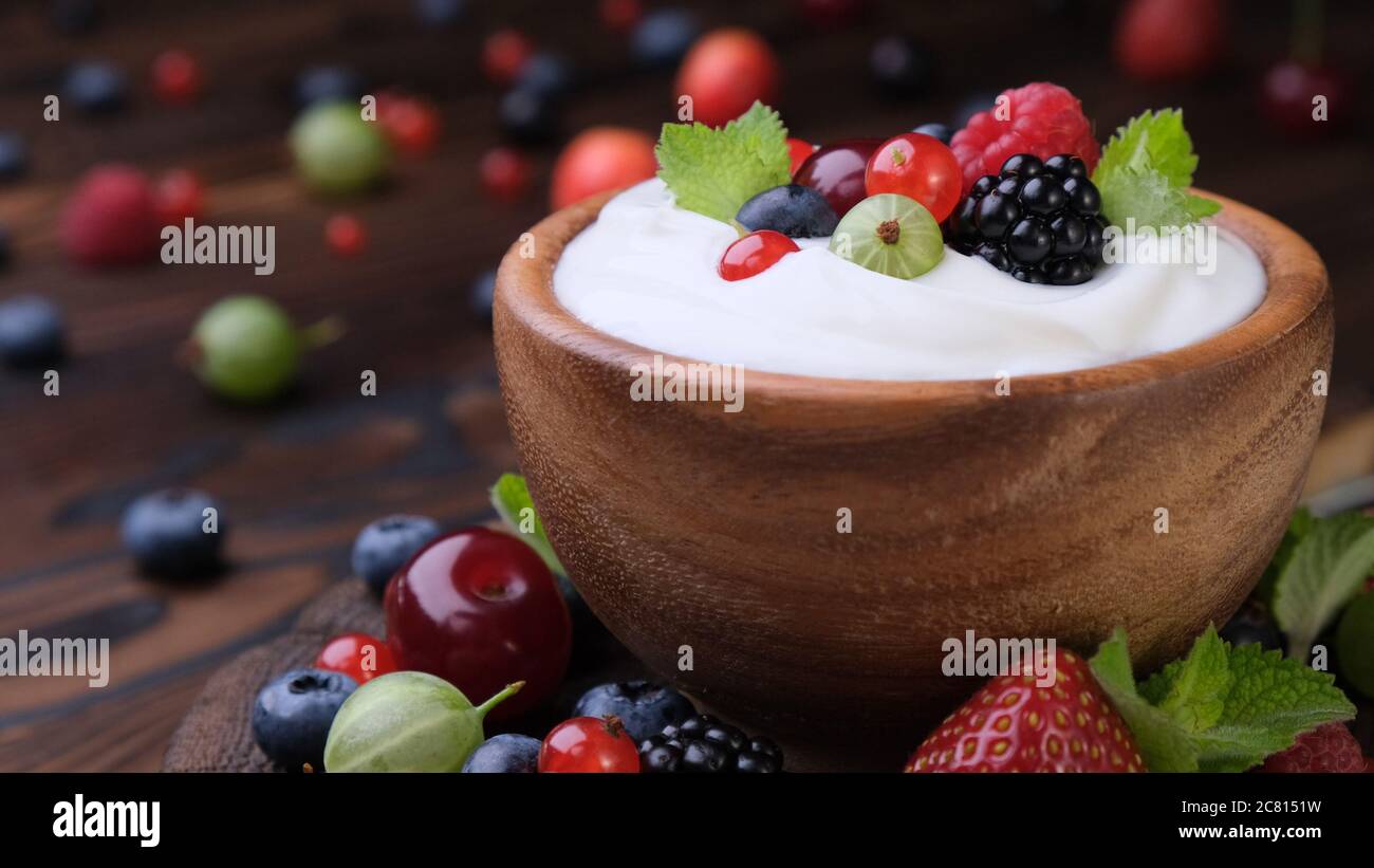 Ciotola di yogurt con frutti di bosco su sfondo di legno scuro Foto Stock