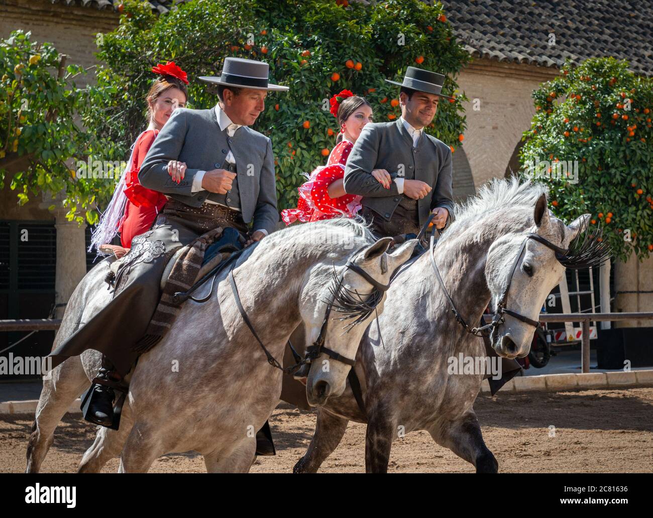 Uomini e donne a cavallo. Quattro piloti in costume spagnolo tradizionale che condividono due cavalli in una dimostrazione equestre presso la Royal Stables Córdoba Foto Stock