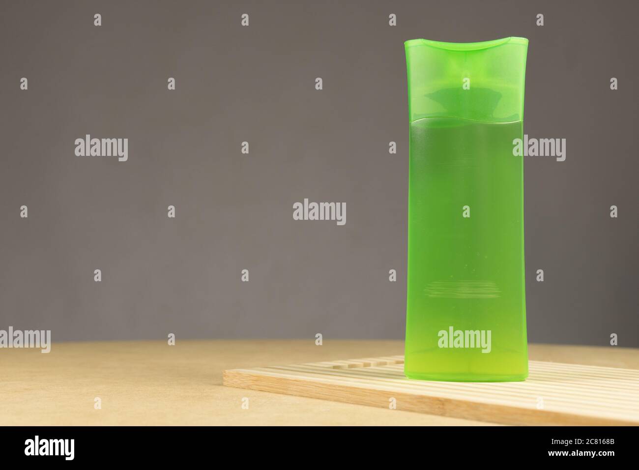 Tubo di plastica verde con shampoo isolato su sfondo grigio. Su un legno Foto Stock