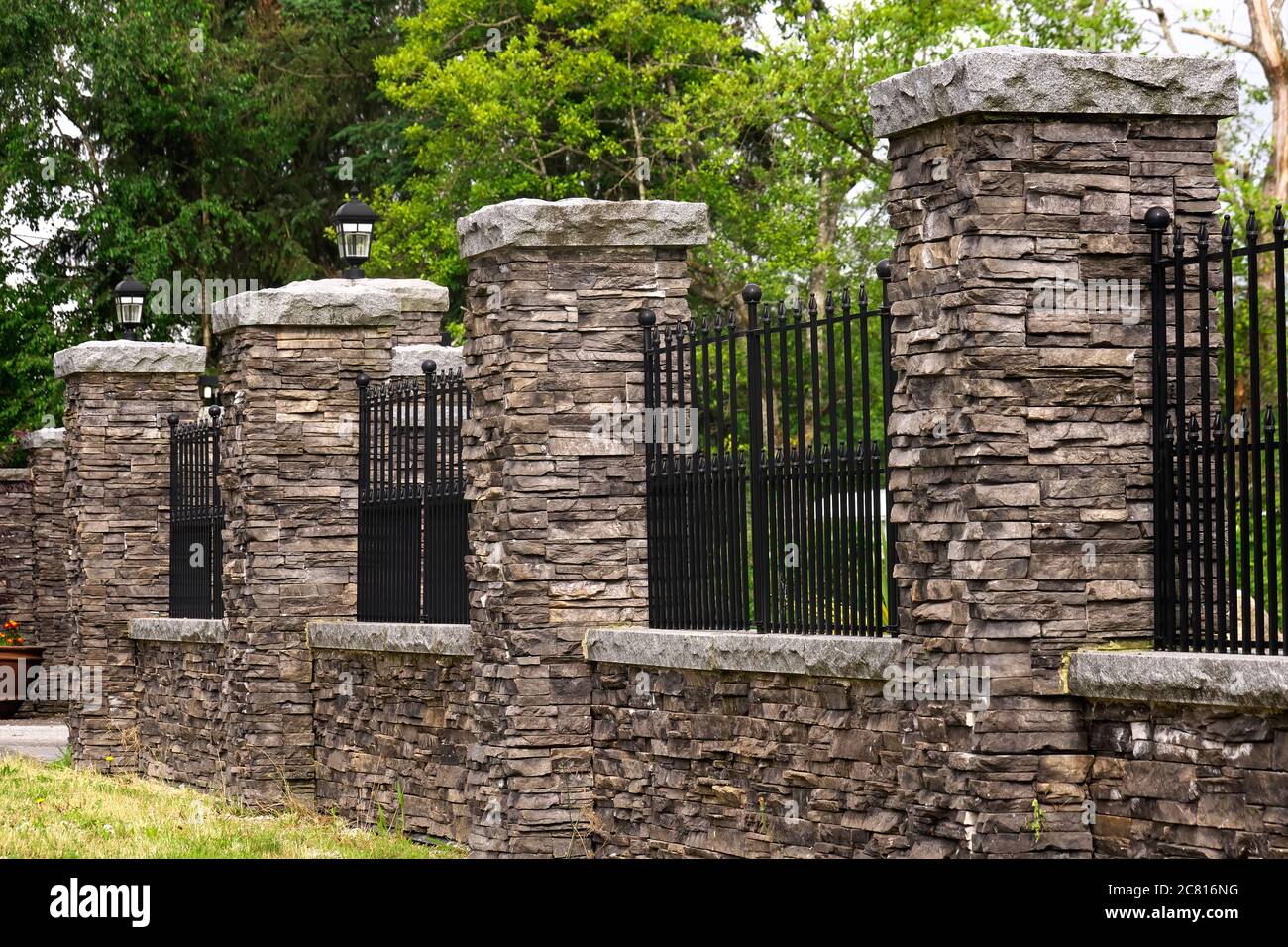 Una recinzione in pietra con intarsi in ferro battuto nero sulla parte anteriore di una proprietà residenziale in Maple Ridge, B. C. Canada. Foto Stock